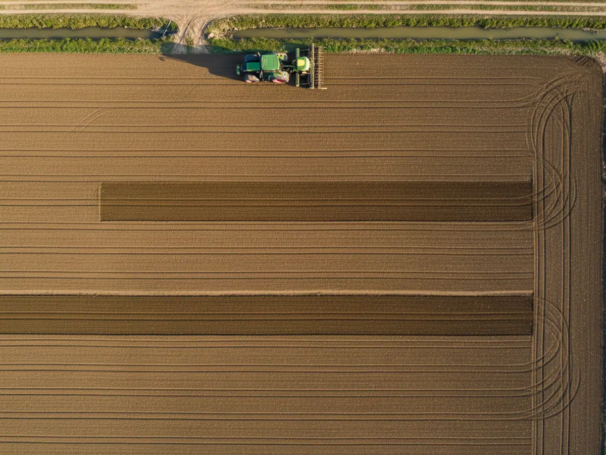 A view from above of a sown field: the seed drill passes overlap in places, a tractor stands at the edge