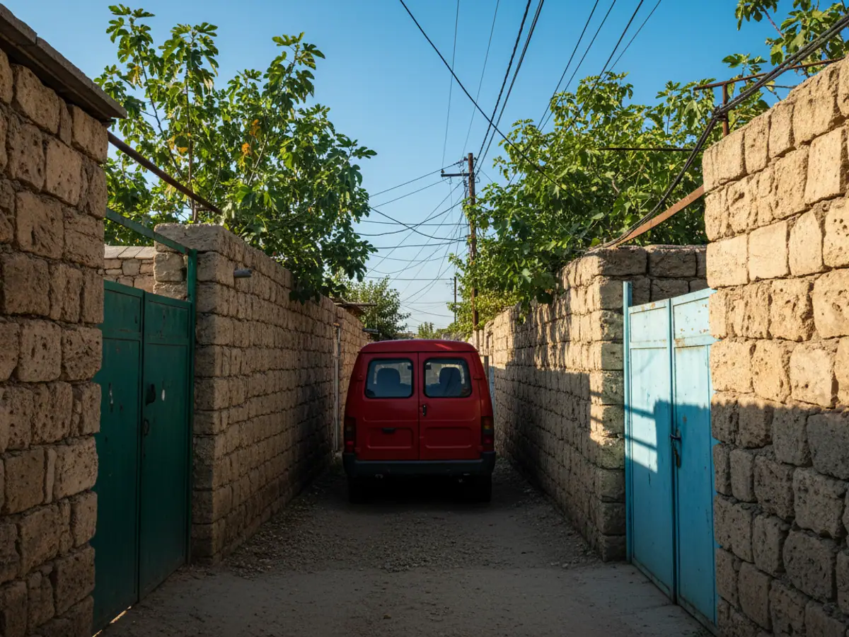 A red van in a narrow lane of an Absheron village between high stone walls