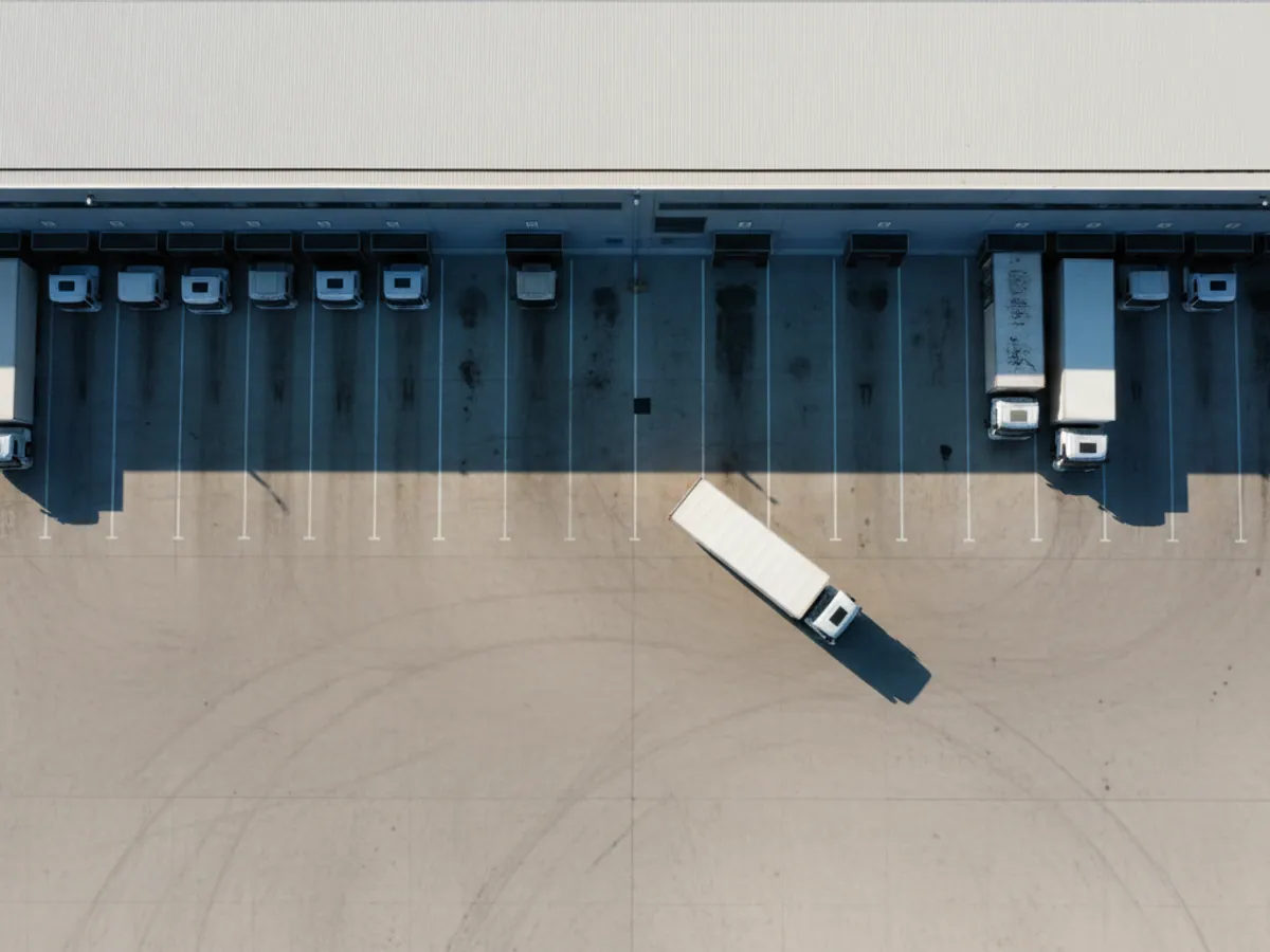 An aerial view of the loading docks of a distribution centre with refrigerated lorries and one free dock